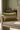 Green pillow with a red stripe on a beige sofa against a green wall.