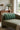 Green striped pillow on a beige sofa with a lamp and plant in the background